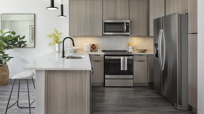 Cocina de apartamento con electrodomésticos de acero inoxidable, encimeras de cuarzo y suelos que imitan la madera. - Griffis Cheesman Park