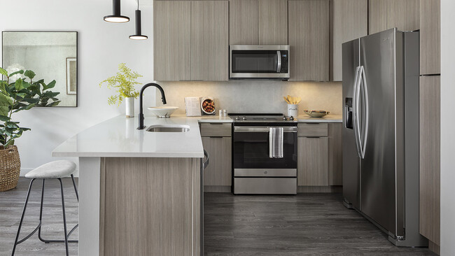 Cocina del apartamento con electrodomésticos de acero inoxidable, encimeras de cuarzo y suelos de madera. - Griffis Cheesman Park