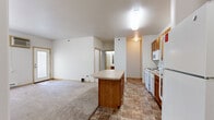 Located at 1820 Dakota Dr N in Fargo, North Dakota, this single-floor residence offers two bedrooms and three bathrooms within a practical and well-organized layout. The kitchen serves as a functional centerpiece, featuring warm honey-toned wood cabinetry, white appliances including a range, microwave, dishwasher, and full-size refrigerator, and a peninsula island that extends into the adjoining living area. Stone-look tile flooring runs throughout the kitchen, providing easy maintenance and a cohesive aesthetic. The bedrooms are carpeted and offer a quiet, comfortable atmosphere, with windows that allow natural light to fill each room. Baseboard heating units are present throughout, ensuring warmth during North Dakota winters. The primary bedroom is generously sized, complemented by an adjacent walk-in closet with wire shelving for ample storage. The three bathrooms are finished with the same tile flooring as the kitchen, and feature wood-toned vanities with countertops. At least one bathroom includes a full tub-shower combination with chrome fixtures. A dedicated closet provides additional storage convenience. The overall design is clean and straightforward, with neutral tones throughout creating a bright, move-in-ready environment.