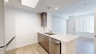 Located at 4343 East Arkansas Avenue in Denver, CO, this one-bedroom, one-bathroom residence offers a thoughtfully designed layout on a single floor. The interior features a contemporary aesthetic defined by crisp white walls, light wood-style flooring throughout the main living areas, and a clean, modern finish.

The kitchen is a standout feature, equipped with stainless steel appliances including a refrigerator, range, built-in microwave, and dishwasher. Dark wood-toned cabinetry — spanning both upper and lower cabinets — contrasts elegantly with the white quartz-style countertops. A peninsula counter extends the workspace and provides an opportunity for casual dining or additional prep area. A skylight-style ceiling fixture adds brightness to the kitchen space.

The living area flows naturally from the kitchen in an open-concept fashion, offering a welcoming and functional space. The bedroom is carpeted for comfort, features a large window with vertical blinds that allows abundant natural light to filter in, and is served by two closets for ample storage.

The bathroom is finished with the same cohesive design language, featuring a dark wood-toned vanity with white countertop, a large mirror, and light wood-style flooring. A walk-in shower and a separate bathtub complete the bathroom's practical offerings. The overall ambiance of the unit is clean, bright, and move-in ready.