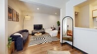 Located at 123 E McCullough Dr in Charlotte, NC, this efficiently designed single-floor unit offers a well-organized layout that maximizes its compact footprint. The open living area is bright and inviting, featuring warm hardwood-style flooring, recessed lighting, and a large window fitted with blinds that allows natural light to fill the space. The living area comfortably accommodates both a seating arrangement and a dining area, making it a versatile and functional space for everyday living. A secondary room provides additional flexibility, featuring its own window with natural light, a wall-mounted HVAC unit for climate control, and hardwood-style flooring consistent with the rest of the unit. The kitchen is efficiently laid out with wood-toned cabinetry, white countertops, a coil-top electric range with overhead ventilation, and a full-size refrigerator — providing all the essential cooking amenities in a streamlined space. The bathroom is clean and straightforward, offering a shower with a curtain, a toilet, a vanity with a white countertop, and hardwood-style flooring. Throughout the unit, neutral white walls and consistent flooring create a cohesive, light, and airy atmosphere suited to a variety of lifestyles.