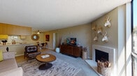 Located at 12556 Oak Knoll Rd in Poway, California, this single-floor residence offers a well-organized and comfortable layout throughout. The spacious living room serves as the heart of the home, anchored by a tile-surround fireplace and featuring large floor-to-ceiling windows that invite abundant natural light and outdoor views. Carpeted flooring, a ceiling fan, and room for generous seating arrangements contribute to its welcoming ambiance.

Adjacent to the living area, the dining space accommodates a round table with seating for four, accented by a sunburst mirror and a ceiling fan overhead. Tile flooring flows naturally into the nearby kitchen, which is outfitted with oak cabinetry, ample counter space, a full-size refrigerator, and a dishwasher — providing practical functionality in a compact, efficient layout.

The home includes two bedrooms, each carpeted and featuring windows with outdoor views. The primary bedroom is generously proportioned with room for a full furniture suite, while the second bedroom offers a cozy, well-lit retreat. Two bathrooms serve the residence, each featuring oak vanities with solid-surface countertops, large framed mirrors, and tile flooring, with one including a shower-tub combination.