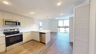 Located at 249 Northwest 6th Street in Miami, FL, this modern single-floor residence offers three bedrooms, two bathrooms, and two closets within a thoughtfully designed layout. The open-concept living and kitchen area serves as the heart of the unit, featuring warm wood-tone flooring that flows throughout. The kitchen is outfitted with sleek, flat-front cabinetry in a crisp white finish, a full suite of stainless steel appliances including a refrigerator, range, over-the-range microwave, and dishwasher, as well as a peninsula with a white quartz countertop illuminated by pendant lighting above. Floor-to-ceiling windows in the living area and bedrooms flood the space with natural light while offering open views of the surrounding Miami cityscape. Each bedroom maintains a clean, minimalist aesthetic with the same wood-tone flooring and large windows. The primary bedroom provides a comfortable footprint with ample wall space. Both bathrooms feature light tile flooring and crisp white finishes; the full bath includes a glass-enclosed walk-in shower, a white vanity, and modern fixtures, while the secondary bath offers a clean, functional layout. The overall design emphasizes contemporary, efficient living in a bright and well-appointed Miami residence.