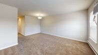 Located at 4065 Harbour Dr in Palmyra, NJ, this single-floor, two-bedroom, one-bathroom home offers a practical and comfortable layout. The living area is finished with warm, neutral-toned carpet and clean white walls, creating a bright and welcoming atmosphere. A pendant light fixture anchors the space, while baseboard heating and a wall-mounted air conditioning unit ensure year-round comfort.

The kitchen is well-appointed with stainless steel appliances, including an electric range, built-in microwave, and dishwasher. Dark countertops contrast with light wood cabinetry, some featuring glass-front upper doors, and the space is finished with durable hardwood-style flooring.

The spacious primary bedroom is notably generous, offering room for a full bedroom suite. It features two side-by-side bi-fold closets, providing ample storage. The second bedroom is carpeted and includes a wall AC unit, baseboard heating, and a door with natural light access. Both bedrooms feature neutral carpet and soft, neutral wall tones.

The bathroom is clean and functional, featuring a full tub-shower combination with a curved curtain rod and white surround panels. Natural light from multiple windows throughout the home adds to the open, airy feel of this well-maintained residence.