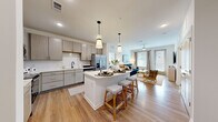 This well-appointed 2-bedroom, 2-bathroom residence offers a thoughtfully designed single-floor layout that maximizes both comfort and functionality. The open-concept kitchen and living area serves as the heart of the home, anchored by a large center island with seating for multiple guests, illuminated by stylish pendant lighting. The kitchen features light wood-tone cabinetry extending to the ceiling, a white quartz countertop, a subway tile backsplash, stainless steel appliances including a French door refrigerator, dishwasher, and range, and a sleek matte black faucet. Light hardwood flooring runs throughout the main living areas, seamlessly connecting the kitchen to the bright, airy living room, which is bathed in natural light through large windows with floor-length drapes and a ceiling fan overhead. Both bedrooms are carpeted and well-sized, with the primary bedroom offering generous closet space and a dedicated en-suite bathroom. The primary bath features dual sinks, light wood-tone vanity cabinetry, quartz countertops, and a glass-enclosed shower. A spacious walk-in closet with wire shelving completes the primary suite. The second bedroom is equally inviting with large windows and ample natural light. Each room reflects a clean, contemporary aesthetic throughout.