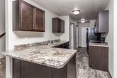 This two-floor residence offers a functional and cohesive interior design characterized by neutral wall tones, textured ceilings, and dark espresso-stained cabinetry that appears consistently throughout the space. The kitchen is well-appointed, featuring dark lower and upper cabinets with brushed nickel hardware, granite-look laminate countertops, a stainless steel double sink, and black appliances including a refrigerator, electric range, and dishwasher. Wood-look plank flooring runs through the kitchen and main living areas, lending warmth and visual continuity across the space.

The open living and dining area is illuminated by ceiling fans with integrated lighting and a small chandelier, contributing to a welcoming atmosphere. A dedicated entry door leads directly into the main living space. Bedroom areas include ceiling fans and a mix of wood-look flooring and plush carpeting, offering comfort underfoot. Windows allow natural light to filter in, enhancing the overall brightness of the rooms.

The bathroom is cleanly finished with a tub-shower combination, a dark-framed vanity mirror, dark cabinetry, and wood-look flooring. A dedicated laundry area houses a full-sized top-load washer and dryer with overhead shelving, adding significant practical value to the space.
