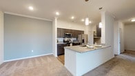 This single-story residence offers two bedrooms and two bathrooms within a thoughtfully designed open-concept floor plan. The kitchen serves as a central highlight, featuring dark espresso cabinetry, granite countertops, a subway tile backsplash, stainless steel appliances, and pendant lighting above a spacious island with a built-in sink. Wood-look flooring runs throughout the kitchen and wet areas, while plush carpeting extends into the living areas and bedrooms. Crown molding and recessed lighting add refined detail throughout.

The living area is generously sized, finished with a ceiling fan and sliding glass doors that open to a private balcony, offering open outdoor views. An arched architectural detail and built-in shelving provide additional character to the common areas.

Both bedrooms are carpeted and well-lit, with the secondary bedroom featuring a large window framing scenic exterior views. The primary bedroom connects to an en-suite bathroom equipped with a granite-topped dark vanity, wood-look flooring, and a walk-in closet with wire shelving. The second bathroom mirrors the same refined finishes and includes a soaking tub with a shower combination.