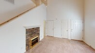 Located at 177 Clusters Circle in Mooresville, NC, this two-story home offers a functional and comfortable layout across both levels. The living room is an immediate highlight, boasting soaring vaulted ceilings that lend an open, airy feel and a striking stone-surround fireplace with a classic white mantel as the room's focal point. Soft carpeting runs throughout the main living and bedroom areas, adding warmth underfoot.

The kitchen is well-equipped with rich warm-toned cabinetry extending to the ceiling, a tile backsplash, ample counter space, a double-basin stainless steel sink positioned beneath a window, and white appliances including a range, over-the-range microwave, and refrigerator. Light hardwood flooring completes the kitchen's inviting look.

The bedrooms are generously sized, each featuring plush carpeting and natural light from windows with blinds. A standout bedroom features an elegant tray ceiling with a ceiling fan, enhancing the sense of space. Bathrooms include a full bath with a tub/shower combination and tile flooring, as well as a vanity bathroom with a wide mirror and warm cabinetry. The textured ceilings are consistent throughout, and the neutral color palette makes the home feel bright and move-in ready.