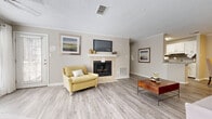 This single-story residence in Hoover, Alabama offers a well-organized layout with two bedrooms and two full bathrooms. The entryway welcomes residents with wood-look plank flooring that continues throughout the main living areas, providing a clean and cohesive aesthetic.

The open-concept living and dining area is generously proportioned, allowing for flexible furniture arrangements. Natural light filters in through multiple windows, and the neutral wall tones complement the light flooring. Crown molding accents the living area, adding a refined detail to the space. The dining area connects seamlessly to the kitchen, which features white cabinetry with brushed nickel hardware, granite countertops, a tile backsplash, black appliances, and a dedicated in-unit laundry closet with a stacked washer and dryer.

Both bedrooms are carpeted and equipped with ceiling fans. The primary bedroom includes direct access to an en-suite bathroom and features a tray ceiling detail. The second bedroom offers exterior door access and multiple windows. Both bathrooms are finished with granite-topped vanities, wood-look flooring, and tub-shower combinations with curved curtain rods.