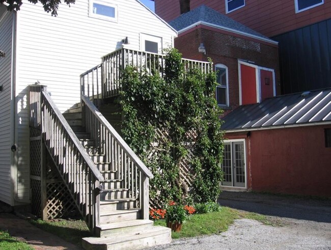 Just steps from the parking area, you are lead to a small private deck with bistro table and the back entrance to your apartment. - 256 Main St