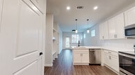 Located at 10951 Netherly Dr in Charlotte, NC, this well-designed single-floor, one-bedroom, one-bathroom home makes excellent use of its space through a thoughtful, open layout. The kitchen serves as a central highlight, featuring crisp white shaker cabinetry, light quartz countertops, a subway tile backsplash, and a full suite of stainless steel appliances including a refrigerator, range, microwave, and dishwasher. A peninsula with a undermount sink and pendant lighting above adds both functionality and style. Wood-look plank flooring runs throughout the main living areas, providing a warm, cohesive aesthetic. The living room is bright and welcoming, with multiple windows fitted with white blinds and a glass door that invites natural light and outdoor views. The bedroom is finished with plush carpet, a ceiling fan, and a well-sized window overlooking the exterior. The bathroom is cleanly appointed with white cabinetry, a light countertop, and wood-look flooring, with access to a walk-in closet featuring built-in shelving. Throughout the home, modern two-panel interior doors with matte black hardware add a clean, contemporary touch, tying together the neutral color palette and modern design elements.