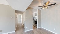 This 2-bedroom, 1-bathroom single-floor residence offers a thoughtfully designed layout with a clean, neutral color palette and updated finishes throughout. The living room is a bright, welcoming space featuring wood-style flooring, a ceiling fan with light fixture, and a sliding glass door that floods the room with natural light. A standout feature is the full-height white-painted brick fireplace, which serves as a striking focal point and adds warmth and character to the living area. The kitchen is efficiently appointed with granite countertops, a stainless steel refrigerator and range, gray shaker-style cabinetry, an under-cabinet range hood, and a stainless steel sink — all combining to create a functional and modern cooking space. A hallway connects the main living area to the bedrooms, bathroom, and closet. Both bedrooms are carpeted and feature sliding door closets with built-in shelving and natural light from windows. The primary bedroom offers a generous footprint with ample closet space. The bathroom includes a full tub-shower combo with white surround, a granite-topped vanity, and clean white fixtures. A dedicated walk-in closet with dual hanging rods and carpet flooring provides additional storage for the home.