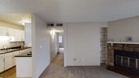 This two-bedroom, one-bathroom residence in Aurora, Colorado offers a well-organized single-level layout designed for comfortable everyday living. The spacious living room serves as the heart of the unit, featuring plush carpeting, a striking stone-surround wood-burning fireplace, built-in shelving, and sliding glass door access to a balcony that fills the room with natural light. A textured ceiling runs throughout the main living areas, lending a classic character to the space.

The galley-style kitchen is thoughtfully laid out with white cabinetry, dark countertops, wood-look flooring, and a full suite of white appliances including a range, dishwasher, and refrigerator. An adjacent hallway connects the kitchen to the rest of the unit, maintaining a functional flow throughout.

Both bedrooms are carpeted and feature vertical blind-covered windows that provide natural light and privacy, along with closet storage. The full bathroom includes a white vanity with dark countertop, a large mirror, wood-look flooring, and a shower/tub combination with a window for added ventilation. The overall palette of neutral tones creates a clean, move-in-ready environment throughout the home.