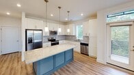 Located at 2729 South Blvd in Charlotte, NC, this single-floor residence offers a thoughtfully designed open layout with contemporary finishes throughout. The living area features light wood-tone flooring, recessed lighting, and a ceiling fan, with multiple windows fitted with blinds that invite natural light and offer views of the surrounding greenery and cityscape.

The kitchen serves as a focal point of the home, showcasing white shaker-style cabinetry, light granite countertops with a subtle veining pattern, and a soft gray subway tile backsplash. A large center island with a distinctive blue base provides additional workspace and seating. Stainless steel appliances, including a refrigerator with ice maker, range, microwave, and dishwasher, complete the well-equipped space. Pendant lighting above the island adds a refined touch.

The bedrooms feature plush carpeting, ceiling fans, and generous windows that frame outdoor views. The primary bathroom is well-appointed with a dual-sink vanity topped with granite, dark cabinetry, wood-look flooring, and a soaking tub. A walk-in closet connects directly to the primary bath, offering practical storage. The clean, neutral color palette throughout the home creates a cohesive and inviting atmosphere.