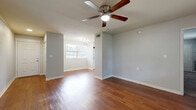 This well-appointed one-bedroom, one-bathroom home in Daytona Beach, FL offers a comfortable and functional single-floor layout. The open living area makes a strong first impression with rich hardwood flooring, neutral gray walls, and a ceiling fan that enhances airflow throughout. Natural light filters in through multiple windows fitted with blinds, creating a bright and welcoming atmosphere. The space flows seamlessly into the kitchen, which is equipped with stainless steel appliances including a refrigerator, range, and microwave, complemented by granite countertops, white cabinetry, and clean tile flooring. Track lighting overhead adds a modern touch to the culinary space. The generously sized bedroom features plush wall-to-wall carpeting, a ceiling fan, and an expansive double closet that provides abundant storage. An additional door in the bedroom offers further convenience. The bathroom includes a full soaking tub with a tiled surround accented by decorative gray tile detailing, tile flooring, and a window that brings in natural light. Throughout the home, clean white baseboards and neutral paint tones create a cohesive, move-in-ready aesthetic suited for comfortable everyday living.