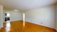 Located at 9010 Patterson Ave in Henrico, Virginia, this single-floor, 2-bedroom, 1-bathroom home offers a practical and comfortable layout. Warm hardwood flooring flows throughout the living areas and bedrooms, lending a cohesive and inviting feel to the space. The living room is open and well-proportioned, bathed in natural light and offering a clean, neutral canvas for personalization. The kitchen features dark gray cabinetry, stone-toned countertops, tile flooring, and includes a refrigerator and dishwasher, with a window providing natural light. A pantry adjacent to the kitchen adds useful storage capacity. The primary bedroom is a comfortable size, with hardwood floors and access to the hallway. The second bedroom also features hardwood floors and a window with views of surrounding greenery. Both bedrooms are serviced by three closets distributed throughout the home, providing generous storage. The bathroom includes a tiled tub-shower surround in neutral tones, a white vanity with countertop, and a mirror. A central hallway connects the rooms efficiently. With a clean, minimalist design and practical amenities, this home presents a functional living environment in a well-established Henrico neighborhood.