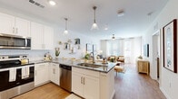 This single-floor residence is designed with a clean, contemporary aesthetic that prioritizes open living and functional flow. The kitchen serves as a central highlight, outfitted with white shaker cabinetry, granite countertops, a subway tile backsplash, and a full suite of stainless steel appliances including a refrigerator, range, microwave, and dishwasher. A generously sized island with seating provides additional prep space and doubles as a casual dining area, illuminated by elegant pendant lighting overhead.

The kitchen opens seamlessly into the living area, which is bathed in natural light from a bank of large windows dressed with sheer curtains. Hardwood-style flooring runs throughout the main living spaces, while a ceiling fan adds both style and practicality. The living room offers ample room for multiple seating arrangements and benefits from bright, neutral walls that enhance the airy atmosphere.

The bedrooms are carpeted for comfort, each featuring ceiling fans, large windows, and generous proportions. The bathroom continues the refined finishes seen throughout, with a granite-topped vanity, white cabinetry, a large mirror, and a tub-shower combination. Overall, the space presents a cohesive, light-filled environment with consistent upscale finishes.