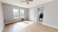 Located at 425 W Tennessee St in Florence, Alabama, this single-floor loft unit offers a clean, functional layout with a refreshed, modern aesthetic. The main living area is a standout feature, showcasing light-toned hardwood flooring that reflects abundant natural light streaming in through large, multi-pane windows. Soft gray walls and crisp white trim create a neutral, welcoming atmosphere, while a ceiling fan overhead adds both style and practicality. A closet and open passageway connect the living space to the rest of the unit seamlessly. The kitchen is well-appointed with white shaker-style cabinetry, warm-toned countertops, and stainless steel appliances including a refrigerator and range. Light ceramic tile flooring and a window above the sink keep the space bright and easy to maintain. The bathroom continues the clean aesthetic with full white subway tile surrounding a soaking tub, complemented by a natural light source from a window. Throughout the unit, consistent neutral tones, white doors with classic paneling, and hardwood flooring tie the spaces together cohesively. This loft offers a practical and comfortable living environment in a convenient Florence location.