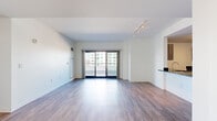 Located in the heart of downtown Stamford, CT, this well-appointed three-bedroom, two-bathroom residence offers a thoughtfully designed single-floor layout with modern finishes throughout. The open-concept living and kitchen area serves as the centerpiece of the space, featuring light hardwood-style flooring, track lighting, and large sliding glass doors that lead directly to a spacious private terrace. The terrace offers panoramic views of the Stamford skyline, making it a standout feature of the residence. The kitchen is outfitted with stainless steel appliances, dark countertops, a built-in island with a sink, and a combination of dark cabinetry and wood-toned upper cabinets. The three bedrooms are carpeted for comfort, each featuring closets with built-in shelving and white panel doors. The hallway connects the bedrooms and bathrooms in a clean, efficient layout. Both bathrooms are finished with neutral tile flooring; one features a floating wood-toned vanity with a white countertop and a tub-shower combination, while the other offers white subway tile surrounding the tub and brushed gold fixtures. Clean white walls and a neutral color palette throughout give the space a bright, contemporary ambiance well-suited to urban living.