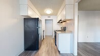 This 2-bedroom, 2-bathroom single-floor unit offers a practical and well-organized layout designed to maximize usable living space. The galley-style kitchen runs along a central corridor, featuring white cabinetry with ample upper and lower storage, light granite-style countertops, black appliances including a refrigerator, electric range, and dishwasher, and wood-style plank flooring that extends throughout the unit. A window at the end of the kitchen allows natural light to filter in, and a ceiling fan adds comfort to the adjacent living area.

The two bedrooms are comfortably sized, with the primary bedroom offering generous square footage. Both rooms feature neutral white walls, wood-style flooring, and textured ceilings, creating a clean and versatile backdrop. Sliding closet doors in at least one bedroom provide accessible built-in storage.

The two bathrooms are finished consistently, each equipped with a white vanity, granite-style countertop, mirrored medicine cabinet, and wood-style flooring. The full bathroom includes a tub-shower combo, while the second bathroom functions as a half or three-quarter bath. Throughout the unit, the consistent use of light tones, wood-style flooring, and white finishes creates a cohesive, move-in-ready aesthetic.