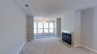 Located at 450 Johnny Mercer Blvd in Savannah, Georgia, this single-floor residence offers a comfortable and functional layout with a clean, neutral aesthetic throughout. The main living area features plush carpeting, a tile-surround fireplace, and a textured ceiling, creating a warm and inviting atmosphere. A distinct windowed nook adjacent to the living room is lined with a bank of large windows on three sides, allowing abundant natural light to flood in while offering pleasant views of the surrounding greenery. This sun-drenched space features wood-look flooring and a ceiling fan, making it an ideal spot for relaxation. The open-concept dining and living area transitions seamlessly toward the kitchen, which is accessible via a pass-through counter. The kitchen is well-equipped with white cabinetry, light countertops, stainless steel appliances including a range, dishwasher, and refrigerator, a double-basin sink, and track lighting overhead. Wood-look flooring extends through the dining area and kitchen. The bathroom is neatly appointed with a single vanity featuring a speckled countertop, a tub-shower combination, and wood-look tile flooring. Throughout the space, neutral tones and consistent finishes create a cohesive and move-in-ready environment.