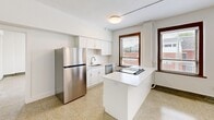 Located at 835 Van Buren St in Fort Wayne, Indiana, this one-bedroom, one-bathroom unit offers a well-organized layout across a single floor. The space is defined by its distinctive terrazzo flooring, which flows consistently throughout every room, lending a polished and cohesive character to the interior.

The kitchen is a standout feature, outfitted with white shaker-style cabinetry, white quartz countertops, and a subway tile backsplash. Stainless steel appliances — including a refrigerator, dishwasher, and range — complement the clean, modern aesthetic. A central island provides additional prep and dining space, while multiple windows with dark wood trim frame views of the surrounding neighborhood and invite ample natural light.

The spacious primary bedroom offers a generous footprint, a built-in closet, and a wall-mounted mini-split HVAC unit for individualized climate control. A window with wood-trimmed blinds continues the natural light theme found throughout the unit.

The bathroom is cleanly appointed with a white vanity, a well-lit mirror, and a tiled tub-and-shower combination featuring marble-style wall tile. The unit also includes an in-unit stacked washer and dryer, adding everyday convenience. Overall, the space presents a bright, minimal, and functional design well-suited for comfortable city living.