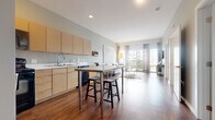 Located at Benchmark Park Drive in Columbus, Ohio, this thoughtfully designed 2-bedroom, 2-bathroom residence offers a functional and modern living experience across a single floor. The open-concept layout seamlessly connects the kitchen, dining, and living areas, creating a cohesive and airy atmosphere throughout.

The kitchen is outfitted with light maple cabinetry, white countertops, black appliances including a refrigerator, range, microwave, and dishwasher, and rich hardwood flooring that extends into the living area. A stainless steel island with bar seating provides a practical dining and prep space.

The living room is bright and inviting, featuring large floor-to-ceiling windows with sheer draping curtains that allow generous natural light and views of the surrounding area. The hardwood flooring continues here, grounding the space with warmth.

The primary bedroom offers carpeted flooring and windows that bring in soft, natural light. The second bedroom mirrors a similar cozy feel. Both bathrooms are clean and functional — one features a tub-shower combo with a dark vanity and chrome fixtures, while the other offers a walk-in shower with tile flooring and a neutral palette. Together, the rooms deliver a comfortable, modern living environment.
