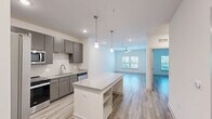 Located at 6000 Front St in Summerville, SC, this well-appointed one-bedroom, one-bathroom unit offers a thoughtfully designed single-floor layout. Light wood-style flooring flows seamlessly throughout every room, creating a cohesive and contemporary aesthetic.

The open-concept kitchen and living area serves as the heart of the unit. The kitchen is equipped with full stainless steel appliances — including a French door refrigerator, range, microwave, and dishwasher — complemented by granite countertops, a subway tile backsplash, and sleek gray cabinetry. A large kitchen island with a granite top provides additional prep space and casual seating. Recessed lighting and pendant fixtures illuminate the area effectively.

The spacious bedroom features a ceiling fan, natural light from a window with blinds, and clean white walls, offering a calm and functional retreat. A dedicated closet provides organized storage space.

The bathroom is finished with granite countertops, a tub-shower combination with tile surround, and coordinating grab bars for added accessibility. Wood-style flooring continues into this space for a uniform look.

A dedicated in-unit laundry room houses a full-size washer and dryer with overhead wire shelving, adding everyday convenience to this practical and modern Summerville residence.