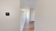 This thoughtfully designed three-bedroom, two-bathroom residence offers a bright and modern living environment across a single floor. Light wood-tone flooring flows consistently throughout every room, creating a cohesive and contemporary aesthetic. The open layout is anchored by a welcoming entrance that connects to a clean, well-lit hallway leading to the main living and private spaces.

The living area is generously proportioned, with large black-framed windows that invite abundant natural light and frame views of surrounding greenery and neighboring architecture. The kitchen features white cabinetry and a clean, minimal countertop design, visible through an open passage from the living space.

Each of the three bedrooms is finished in a neutral palette with the same warm wood flooring. The bedrooms benefit from large windows that offer elevated views of the surrounding urban landscape and tree canopy. Several bedrooms include closets, with at least one featuring a walk-in closet with built-in shelving.

The two bathrooms reflect the same modern sensibility. One features a sleek floating vanity with a white countertop, mirror, and wood-toned cabinetry. The other is more expansive, with a long vanity, tall storage cabinet, and a glass-enclosed shower. Both bathrooms maintain a crisp, clean finish throughout. The overall ambiance of the space is airy, minimal, and move-in ready.