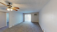 Located at 4467 Colerain Ave in Cincinnati, Ohio, this single-floor unit offers a practical and comfortable layout spread across several well-defined living spaces. The living room is generously sized, featuring wall-to-wall carpeting, a textured ceiling, a ceiling fan, and a wall-mounted air conditioning unit. A large sliding glass door dressed with vertical blinds fills the room with natural light and provides outdoor views, while baseboard heating runs along the perimeter for year-round comfort. The bedroom continues the same carpeted flooring and textured ceiling, equipped with its own ceiling fan and a window overlooking the surrounding neighborhood. A closet is conveniently accessible from the bedroom, adding practical storage. The kitchen is outfitted with warm oak cabinetry offering ample upper and lower storage, light-toned countertops, a double stainless steel sink, and a black electric range. Wood-look flooring grounds the space and complements the cabinetry tones. The bathroom features a clean, white tub and shower surround with built-in shelving niches. Neutral wall colors and consistent finishes throughout lend the unit a cohesive, move-in-ready feel suited for everyday living.