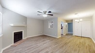 This single-floor residence offers a practical and well-organized layout connecting the main living areas to private bedrooms. The living room serves as the central gathering space, featuring hardwood-style flooring, a ceiling fan with integrated lighting, and a fireplace framed by a classic brick hearth — a functional and visually grounding focal point. Neutral gray walls throughout create a clean, cohesive atmosphere that carries from room to room.

The galley-style kitchen is efficiently designed with white cabinetry, light stone-look countertops, a double-basin sink, and a full suite of stainless steel appliances including a refrigerator, electric range, microwave, and dishwasher. A pass-through opening connects the kitchen visually to the living area, enhancing the sense of openness.

The bedrooms are finished with plush carpet and neutral walls, providing a comfortable and quiet retreat. One bedroom features a window with horizontal blinds, allowing natural light while maintaining privacy. The bathroom is straightforwardly appointed with a tub-shower combination, toilet, hardwood-style flooring, and overhead cabinetry for storage. Overall, the space presents a clean, move-in ready environment with consistent finishes throughout.