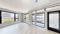 Located at 400 Waterside Drive in Norfolk, Virginia, this well-appointed three-bedroom, two-bathroom residence offers a thoughtfully designed single-floor layout with a clean, modern aesthetic throughout. Light-toned luxury vinyl plank flooring flows through the main living areas, complemented by crisp white walls and bold black hardware accents that lend a contemporary feel to every room.

The open-concept living and kitchen area serves as the heart of the home. The kitchen is outfitted with gray shaker-style cabinetry, white quartz countertops, stainless steel appliances including a side-by-side refrigerator, built-in microwave, and range with a wall-mounted hood vent, plus a dedicated pantry for added storage. The living area extends to a private balcony through floor-to-ceiling black-framed sliding glass doors and transom windows, filling the space with generous natural light and urban views.

The three bedrooms are carpeted for comfort, each offering good proportions and ample closet space — five closets total across the unit. The primary bedroom provides a spacious retreat. Both bathrooms feature white vanities, tub-shower combinations, and consistent matte black hardware. A connecting hallway ties all rooms together efficiently, enhancing the home's functional flow.