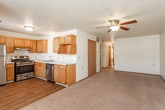 This single-floor unit offers a practical and comfortable layout with clearly defined living spaces throughout. The kitchen is well-appointed with warm oak cabinetry, stainless steel appliances including a gas range, refrigerator, and dishwasher, complemented by a double-basin sink and durable hardwood-style flooring. A ceiling-mounted range hood and ample upper and lower cabinet storage make this an efficient cooking space.

The living area is generously sized, featuring plush wall-to-wall carpeting, a ceiling fan with light fixture, and multiple windows that invite natural light into the room. Neutral-toned walls and wood-trimmed doors carry a consistent aesthetic throughout the space.

Two carpeted bedrooms offer quiet retreats, each with windows fitted with horizontal blinds that provide views of surrounding trees. One bedroom includes a full-size closet with a solid wood door. The textured ceilings and clean baseboards are consistent features across the bedrooms.

Two full bathrooms are present, each with an oak vanity, white countertop with an undermount sink, a toilet, and a full tub-shower combination. Tile flooring in a warm stone pattern adds a durable and easy-to-maintain finish. The bathrooms are efficiently laid out and well-lit, providing functional comfort throughout the unit.