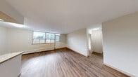 This 2-bedroom, 1-bathroom unit is thoughtfully arranged across a single floor, offering a practical and comfortable layout. The open living and dining area is a standout space, featuring warm hardwood-style flooring, neutral walls, and a wide multi-pane window that draws in generous natural light while framing views of the surrounding cityscape. Baseboard heating runs along the exterior walls, ensuring year-round comfort.

The galley-style kitchen is efficiently designed with medium-toned wood cabinetry, granite-look countertops, a stainless steel sink, and stainless steel appliances, including a refrigerator. Light ceramic tile flooring completes the kitchen's clean, functional aesthetic.

The primary bedroom is a comfortable size, featuring large windows that provide ample natural light and a baseboard heater. The second bedroom also features hardwood-style flooring and a mirrored sliding closet door, adding a sense of depth to the room. A hallway connects the private areas of the unit, providing access to both bedrooms and the shared bathroom.

The bathroom includes a full soaker tub with a tiled surround in a neutral palette, accented by a decorative mosaic border tile. Hardwood-style flooring flows consistently throughout the living spaces, tying the unit together with a cohesive, modern feel.