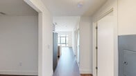 Located on the 15th floor at 42 Broad St W in Mount Vernon, NY, this 2-bedroom, 1-bathroom unit offers a well-designed layout with modern finishes throughout. Warm hardwood-style flooring runs continuously through the living area, bedrooms, and hallways, creating a cohesive and inviting atmosphere.

The open living area flows seamlessly into the kitchen, which is equipped with stainless steel appliances including a full-size refrigerator, microwave, and range. Light wood cabinetry, a quartz countertop peninsula with an undermount sink, and a tile backsplash give the kitchen a clean, contemporary feel.

The primary bedroom is a well-proportioned space featuring large floor-to-ceiling windows that flood the room with natural light and offer elevated views of the surrounding area. The second bedroom also benefits from hardwood flooring and easy access to the main hallway.

The bathroom is finished with large-format marble-look porcelain tile flooring and matching wall tile in the shower enclosure. A wall-mounted vanity with a wood-toned cabinet, integrated sink, and framed mirror completes the sleek design.

A dedicated closet provides practical storage, rounding out the efficient and thoughtfully arranged floor plan of this modern unit.
