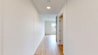Located in Vancouver's vibrant Mount Pleasant neighbourhood, this modern two-bedroom, one-bathroom unit offers a thoughtfully designed layout across a single floor. Light-toned hardwood flooring flows throughout, lending warmth and continuity to the space.

The open living area is bright and airy, anchored by large floor-to-ceiling windows that frame views of the surrounding Vancouver cityscape and neighbourhood rooftops, filling the space with abundant natural light. The kitchen features sleek grey cabinetry, a bold yellow-green tile backsplash, and integrated appliances, adding a contemporary edge to the overall design.

A clean hallway with recessed ceiling lighting connects the living areas to the two bedrooms. The primary bedroom is a compact, well-proportioned room with warm hardwood floors and a sliding closet door, while the second bedroom benefits from its own large window with outdoor views. Both rooms feature crisp white walls, offering a neutral canvas.

The bathroom is finished in a minimalist style, with large-format light tile flooring, a floating vanity with white countertop, full-width mirror, and brushed gold hardware accents that add a subtle touch of elegance. The overall aesthetic is clean, modern, and functional — ideal for those seeking a contemporary urban home in one of Vancouver's most sought-after communities.