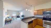 Located in Wilmington, Delaware, this single-floor residence offers a thoughtfully designed open-concept layout that seamlessly connects the kitchen, dining, and living areas. The kitchen is well-equipped with warm-toned wood cabinetry, dark countertops, stainless steel appliances including a refrigerator, range, and microwave, and a peninsula with a sink and dishwasher. A stylish track lighting system with pendant fixtures illuminates the space, complemented by hardwood flooring that transitions to plush carpeting in the living and dining areas. The spacious living room features large windows and French doors that open to a private balcony, filling the space with natural light and offering pleasant outdoor views. The unit includes three bedrooms, each carpeted and well-lit by natural light. The primary bedroom is generously sized, while a secondary bedroom comfortably accommodates twin beds. Two full bathrooms serve the unit — one featuring a glass-enclosed shower stall and the other a shower-tub combination, both with warm wood vanities, white countertops, and tile flooring. Throughout the residence, the neutral color palette and clean architectural lines create a bright, functional, and comfortable living environment.