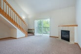Located at 6732 Pinelake Dr in Madison, WI, this two-story home offers a thoughtfully designed layout spread across two floors. The main level features an open-concept living, dining, and kitchen area that immediately impresses with soaring vaulted ceilings and an abundance of natural light. The living room is anchored by a corner fireplace with a tile surround and wood mantle, and sliding glass doors lead to a private patio overlooking a lush, tree-lined green space. The kitchen is well-appointed with warm oak cabinetry, a center island with counter seating, hardwood flooring, and white appliances including a range, dishwasher, microwave, and refrigerator. A built-in shelving unit near the entryway adds functional storage. Upstairs, a wood-railed staircase leads to the spacious primary bedroom, which benefits from a skylight that floods the room with natural light, along with a ceiling fan. The full bathroom features tile flooring, an oak vanity, and a full tub/shower combination. Four closets throughout the home provide ample storage. The patio offers peaceful outdoor views of manicured lawns and mature trees, completing this comfortable and well-appointed Madison residence.