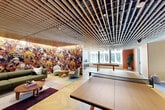 Located at 1070 Bridgeview Way in San Francisco's vibrant Mission Bay neighborhood, this amenity lounge is a thoughtfully designed communal space that blends sophisticated aesthetics with recreational functionality. The single-floor layout is unified by a dramatic slatted wood ceiling that runs throughout, adding warmth and architectural depth to the open, airy environment.

The main area serves as a multi-use gathering space, anchored by a full-size ping pong table and a billiards table positioned near floor-to-ceiling windows that invite abundant natural light and views of the surrounding urban landscape. A statement wall mural — richly illustrated with vivid, nature-inspired imagery in warm autumnal tones — commands attention and adds an artistic focal point to the lounge area, where contemporary seating arrangements encourage casual conversation and relaxation.

Herringbone-patterned hardwood flooring flows seamlessly throughout the space, grounding the design with classic elegance. Semi-private nook areas are tucked thoughtfully within the layout, each outfitted with sectional sofas, accent lighting, and curated artwork, offering more intimate settings within the broader open plan. Steel-framed glass partitions provide subtle visual separation while preserving the sense of openness. The overall ambiance is modern, inviting, and well-appointed — ideal for both social gatherings and leisurely downtime.