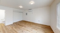 Located at 435 Gateway Dr in Pacifica, CA, this efficiently designed studio unit offers a thoughtfully organized single-floor layout that maximizes every square foot. The open living area is finished with light-toned hardwood-style flooring that runs throughout, lending a clean and cohesive feel to the space. Bright white walls and flush-mount ceiling light fixtures contribute to an airy, well-lit atmosphere. A wall-mounted mini-split air conditioning unit provides year-round climate control, while a utility panel is conveniently recessed into the wall.

The kitchen occupies one end of the main living area and is outfitted with a full suite of stainless steel appliances, including an electric range with oven, a built-in microwave, a dishwasher, and a full-size refrigerator. Sleek gray flat-front cabinetry extends from counter height to the ceiling, offering generous storage. Light-colored countertops and a single-basin sink with a modern faucet complete the functional workspace. Natural light filters into the kitchen area through a nearby window and glass door.

The bathroom features a walk-in shower with a white surround panel system, built-in shelving niches, and a chrome showerhead and valve fixture, providing a clean and practical design. Overall, the unit presents a modern, move-in-ready aesthetic well-suited for streamlined, efficient living.