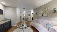 Located at 2355 Austin Highway in San Antonio, TX, this single-story 1-bedroom, 2-bathroom residence offers a thoughtfully designed layout that maximizes every square foot. The open living and dining area is anchored by rich hardwood-style flooring, neutral gray walls, and a textured ceiling, creating a warm and cohesive atmosphere. A sliding glass door in the living room fills the space with natural light and provides direct access to a private patio with outdoor views. The galley-style kitchen features dark cabinetry, light countertops, black appliances, and a window that brings in additional natural light. The dining area flows seamlessly from the kitchen and living space, making entertaining easy. The bedroom is carpeted for comfort, features a ceiling fan with light, and benefits from natural light through well-dressed windows. Three closets, including a spacious walk-in, provide ample storage throughout. The two bathrooms include one with a full tub-shower combination with white tile surround, and another with a wide vanity featuring dark cabinetry and a large mirror. This residence offers a practical and inviting layout suited for comfortable everyday living in San Antonio.