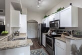 Located at 2080 E Karin Ct in Cottonwood Heights, Utah, this single-floor residence offers a thoughtfully designed layout with a cohesive blend of contemporary finishes and comfortable living spaces.

The kitchen is a functional highlight, featuring a galley-style configuration with white cabinetry extending to the ceiling, granite countertops, stainless steel appliances including a refrigerator, range, and microwave, and hardwood-style flooring. A peninsula provides additional prep space and casual seating. An arched doorway at the end of the kitchen leads to an in-unit laundry area.

The living room features vaulted ceilings with a ceiling fan, hardwood-style flooring, and a warm, open ambiance. An adjacent dining area accommodates a round table set beneath a pendant light fixture and benefits from natural light through a large window with floor-length drapes.

The bedroom is generously proportioned with plush carpeting, vaulted ceilings, a ceiling fan, and a wide window dressed with vertical blinds and curtain panels. A closet with sliding doors provides ample storage.

The bathroom is finished with granite countertops, white cabinetry with brushed nickel hardware, a large wood-framed mirror, hardwood-style flooring, and a shower-tub combination, creating a clean and polished aesthetic throughout.