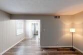 Located at 2200 Dinsmore Dr in Lexington, KY, this one-bedroom, one-bathroom unit offers a thoughtfully utilized single-floor layout. Consistent wood-look vinyl plank flooring runs throughout, providing a cohesive and low-maintenance aesthetic across every room.

The living room serves as the welcoming entry point of the unit, featuring neutral gray wall paneling, a textured ceiling, and a classic six-panel front door. The space transitions smoothly into the kitchen, which is outfitted with light gray cabinetry, white subway tile backsplash, a white electric range, built-in microwave, and a stainless sink — a clean, functional design that opens directly into the living area through a wide doorway.

The bedroom is a comfortable, private retreat with a window allowing natural light, a wall-mounted HVAC unit, and built-in open shelving that provides convenient storage without sacrificing floor space. The neutral wall paneling continues here, maintaining a consistent look throughout the unit.

The bathroom features wood-look flooring that matches the rest of the unit, a white vanity, and a full tub/shower combination with floor-to-ceiling large-format tile in a warm gray tone, lending a modern, updated feel. Overall, the unit presents a clean, refreshed interior well-suited for comfortable everyday living.