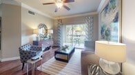 Located at 1600 River Pointe Dr in Conroe, Texas, this well-appointed single-floor residence combines comfort and style throughout its thoughtfully designed layout. Rich hardwood flooring flows through the main living areas, anchoring the warm, cohesive aesthetic of the home.

The living room is a welcoming space adorned with crown molding, a ceiling fan, and large windows dressed with elegant draping curtains that invite abundant natural light. Decorative wall art and tasteful furnishings contribute to a refined yet relaxed atmosphere.

The kitchen is efficiently designed with dark cabinetry, granite-style countertops, and a full suite of stainless steel appliances including a refrigerator, range, and over-the-range microwave. A breakfast bar peninsula provides both additional prep space and a casual dining option, seamlessly connecting the kitchen to the adjacent dining area.

The bedrooms are generously proportioned, each featuring ceiling fans and large windows or sliding glass doors that open to outdoor views, filling the rooms with natural light. Plush carpeting and ample closet space add to the comfort of the private quarters.

The bathroom is well-sized and includes a large vanity with an extended countertop, a soaking tub with tiled surround, hardwood flooring, and a sizeable closet with louvered doors, offering both functionality and a clean, classic aesthetic.