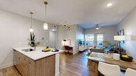 Located at 680 S Calhoun Pl in Star, Idaho, this single-floor residence combines modern design with functional living. The open-concept layout connects the kitchen, dining, and living areas seamlessly, creating a bright and cohesive space. The kitchen is equipped with stainless steel appliances, light wood cabinetry, white quartz countertops, a large island with pendant lighting, and recessed ceiling lights that illuminate the generous workspace. Durable wood-look flooring runs throughout, tying the spaces together with a warm, contemporary feel. The living area accommodates both a comfortable seating arrangement and a dedicated workspace, with a ceiling fan overhead and a glass door providing access to an outdoor area and natural light. A dining space flows naturally between the kitchen and living room. The bedroom is a calm retreat, featuring a window that allows in natural light and modern décor. The bathroom offers a double-sink vanity with wood cabinetry and white countertops, providing ample storage and a clean, finished aesthetic. Throughout the residence, neutral wall tones and thoughtful design choices create a cohesive, inviting atmosphere well-suited for everyday living.