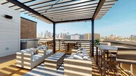 Located in Dallas's vibrant Deep Ellum neighborhood, this rooftop deck at 3008 Taylor St offers a thoughtfully designed outdoor retreat with striking views of the downtown Dallas skyline. The deck features warm wood decking throughout, anchored by a bold steel pergola structure with slatted overhead panels that filter natural sunlight and create dynamic shadow patterns across the space.

Multiple seating zones are defined by patterned area rugs and furnished with comfortable all-weather wicker lounge chairs and sofas dressed in neutral cushions. String lights are strung beneath the pergola, setting the stage for evening gatherings. Lush potted plants and vibrant floral planters add natural color and greenery throughout the deck.

An outdoor entertainment area includes a wall-mounted flat-screen television paired with stainless steel cabinetry and a built-in beverage refrigerator, making it well-suited for hosting. Black-framed glass doors with a steel grid pattern provide access to the interior, while additional dining and bar-height seating areas are positioned to maximize the panoramic city views.

The surrounding brick building facades and open sky contribute to the urban industrial character of the space, while the well-appointed furnishings and amenities create an inviting, resort-like atmosphere ideal for relaxation and entertainment above the Dallas cityscape.