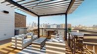 Located in Dallas's vibrant Deep Ellum neighborhood, this rooftop deck at 3008 Taylor St offers a thoughtfully designed outdoor retreat with striking views of the downtown Dallas skyline. The deck features warm wood decking throughout, anchored by a bold steel pergola structure with slatted overhead panels that filter natural sunlight and create dynamic shadow patterns across the space.

Multiple seating zones are defined by patterned area rugs and furnished with comfortable all-weather wicker lounge chairs and sofas dressed in neutral cushions. String lights are strung beneath the pergola, setting the stage for evening gatherings. Lush potted plants and vibrant floral planters add natural color and greenery throughout the deck.

An outdoor entertainment area includes a wall-mounted flat-screen television paired with stainless steel cabinetry and a built-in beverage refrigerator, making it well-suited for hosting. Black-framed glass doors with a steel grid pattern provide access to the interior, while additional dining and bar-height seating areas are positioned to maximize the panoramic city views.

The surrounding brick building facades and open sky contribute to the urban industrial character of the space, while the well-appointed furnishings and amenities create an inviting, resort-like atmosphere ideal for relaxation and entertainment above the Dallas cityscape.