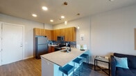 Located at 1001 W Rosedale St in Fort Worth, Texas, this single-floor unit offers a well-designed layout that balances function and modern style. The open-concept kitchen serves as a central highlight, featuring warm wood cabinetry extending to the ceiling, a slate-toned tile backsplash, granite countertops, and a full suite of stainless steel appliances including a refrigerator, electric range with microwave, and built-in sink. A peninsula with granite countertop and seating provides an ideal casual dining or gathering space, illuminated by stylish pendant lighting with brass-toned fixtures.

The living area is bright and welcoming, with a large sliding glass door fitted with vertical blinds that allow natural light to fill the room. Wood-look flooring runs throughout the main living spaces, adding warmth and continuity.

The bedroom features elevated ceilings, dual windows that invite natural light, a ceiling fan, and wood-look flooring. It connects to a spacious walk-in closet with rod storage. The bathroom offers a long granite-topped vanity with dual sinks, warm wood cabinetry, a wide mirror, and clean, neutral finishes that contribute to the overall modern and cohesive aesthetic of the space.