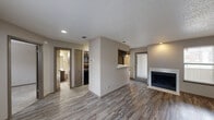 Located at 3715 William Dehaes Dr in Irving, Texas, this single-story residence offers a well-organized, open-concept layout designed for comfortable everyday living. The main living area is bright and welcoming, finished with durable wood-look plank flooring and neutral-toned walls that create a clean, modern aesthetic. A classic fireplace with a white surround serves as a focal point in the living room, complemented by a window with blinds that allows natural light to filter in.

The kitchen is positioned adjacent to the living area and features a pass-through breakfast bar with light granite-style countertops, dark espresso cabinetry, a mosaic tile backsplash, and black appliances including a range and refrigerator. The layout offers efficient use of space with ample cabinet storage overhead.

The bedroom is generously sized, with plush carpet flooring, a ceiling fan with light fixture, and a window providing natural light. It connects directly to a bathroom equipped with a full tub-shower combo featuring white tile surround and polished chrome fixtures. A second bathroom is also accessible from the main living area.

Throughout the space, textured ceilings, recessed lighting, and consistent neutral finishes tie the rooms together cohesively, making this a practical and move-in ready residence in Irving, TX.