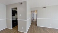 This 2-bedroom, 1-bathroom single-floor unit offers a practical and cohesive layout designed for efficient use of space. Warm wood-look flooring runs throughout the unit, complemented by neutral gray walls and crisp white trim, creating a clean and modern aesthetic. A central hallway connects all rooms, providing a logical flow from the entry to the living areas and bedrooms.

The living room is a comfortable, light-filled space featuring a large window that allows natural light to pour in, along with a two-tone wall treatment with a white chair rail detail. The galley-style kitchen is fitted with bold dark cabinetry on both sides, light granite-style countertops, a double-basin sink, and black appliances including a gas range and refrigerator, making efficient use of the narrow footprint.

Both bedrooms are well-proportioned with wood-look flooring, neutral walls, and large windows that bring in ample natural light. The primary bedroom offers a comfortable amount of space, while both rooms are accessed via striking black six-panel doors that add a consistent design accent throughout the unit. The bathroom includes a full-size tub and shower combo with white tile surround and chrome fixtures. Overall, the unit presents a clean, move-in ready environment with a cohesive neutral palette.
